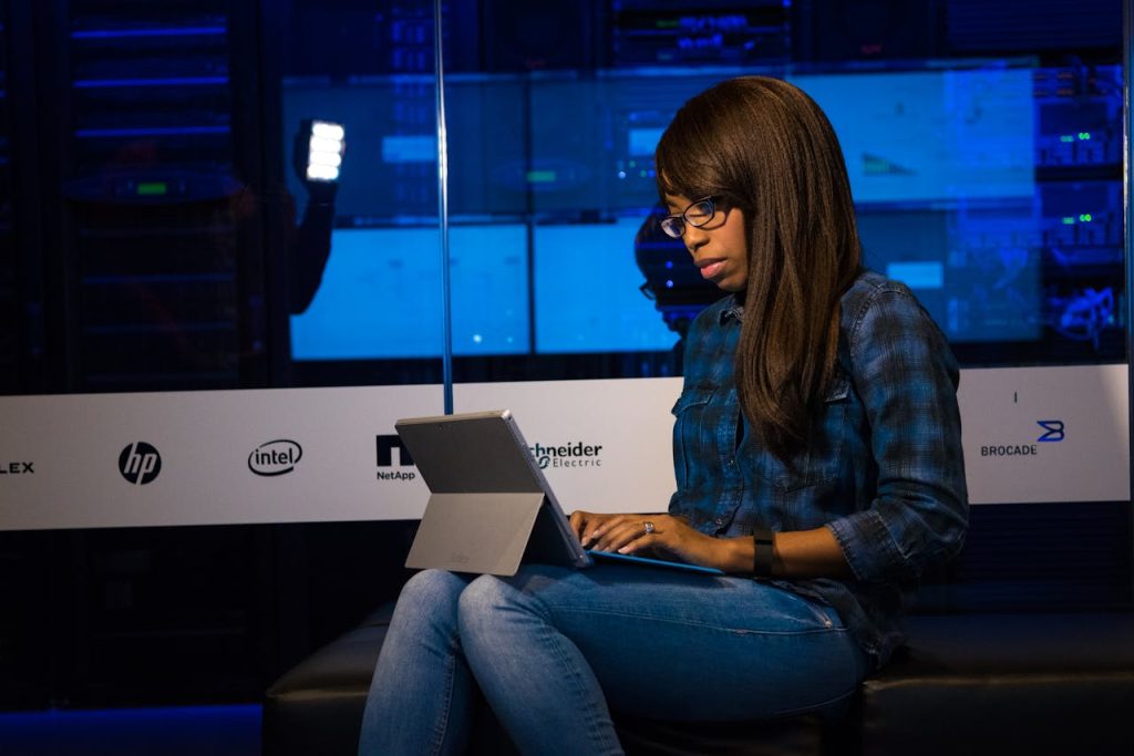 Woman working intently on a laptop in a modern data center environment.
